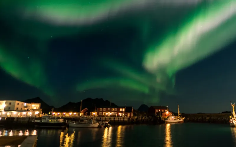 Fishing boats in a quiet northern Norwegian harbour at night with the aurora overhead